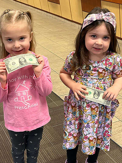 Preschoolers Evelyn Griffith and Madison Boyd pose with their $1 bills.