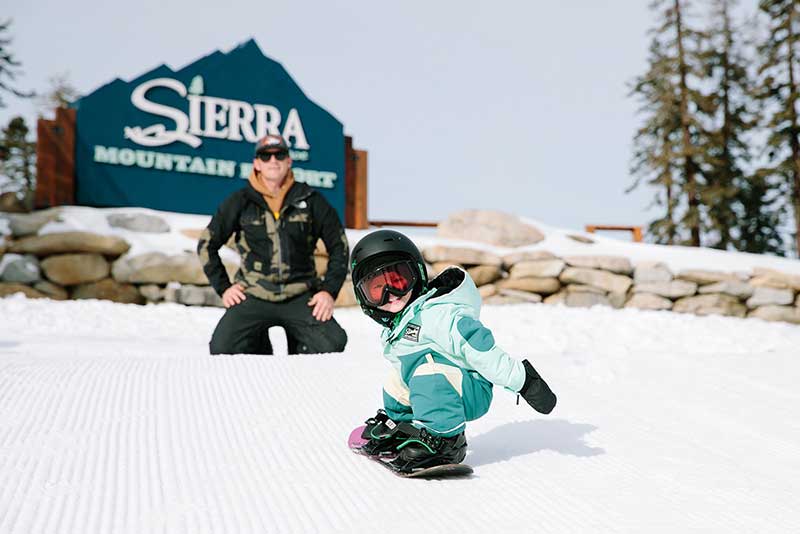 A young snow enthusiast snowboards at Sierra-at-Tahoe Mountain resort.