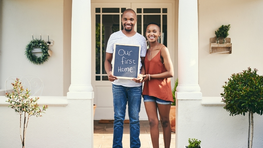 Couple standing in front of their first home